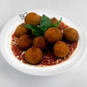 Golden spinach and parmesan arancini on arugula, a crispy Italian cuisine appetizer